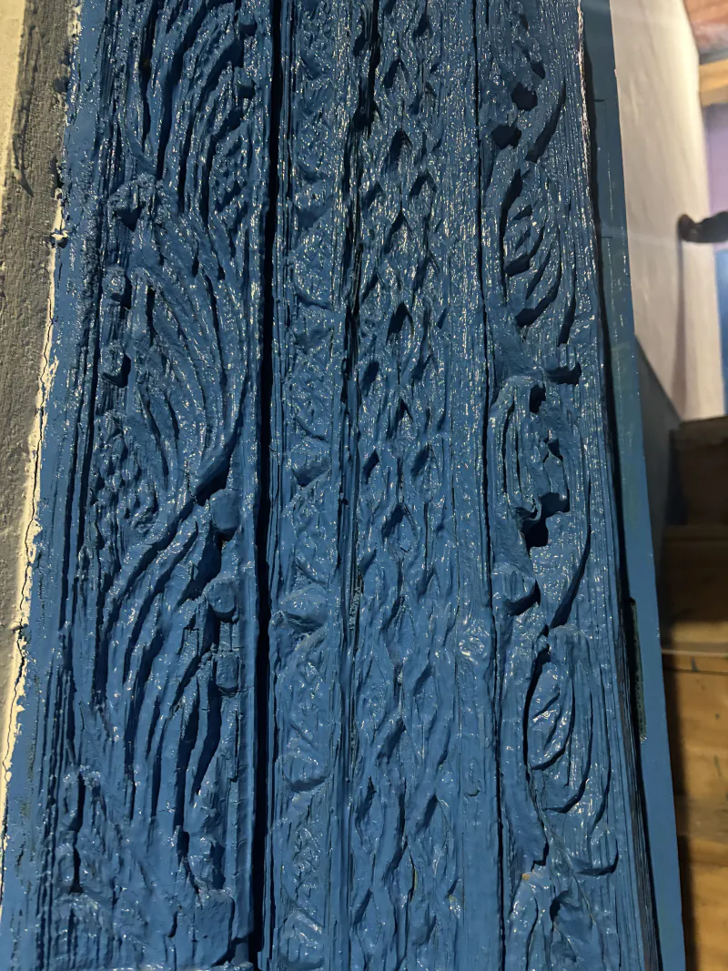 Close-up of the carvings on the blue-painted front door