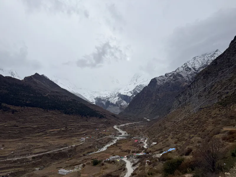 The Darma Valley under grey clouds: terraced fields, a river and a road below snow-covered mountains